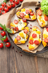 Tasty bruschetta with tomatoes on pan, on old wooden table
