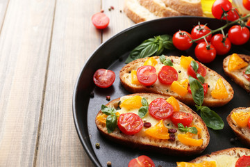 Tasty bruschetta with tomatoes on pan, on old wooden table