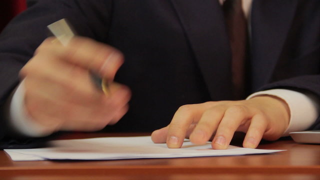 Businessman signs papers, contract, agreement, works on laptop