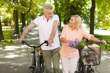 Mature couple walking at park with bicycles