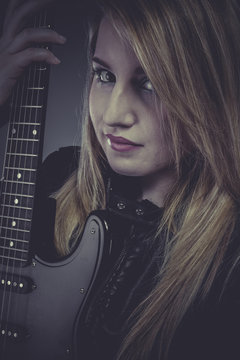 Beautiful blond girl with black electric guitar