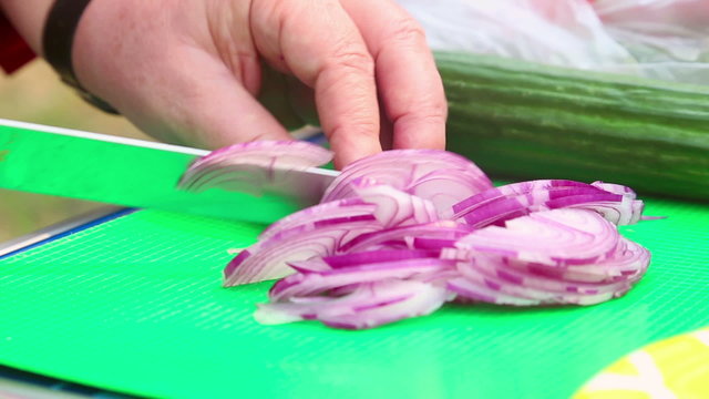 Woman choping onion on a cutting board.