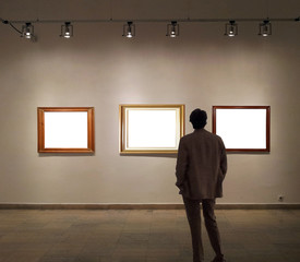Man in gallery room looking at empty picture frames