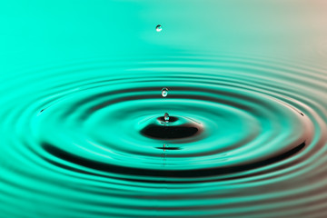 Naklejka na ściany i meble Water drop close up with concentric ripples colourful amberblue