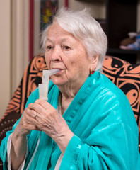 Old woman making an inhalation
