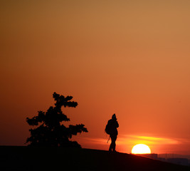 Silhouette of photographer with his equipment during sunset