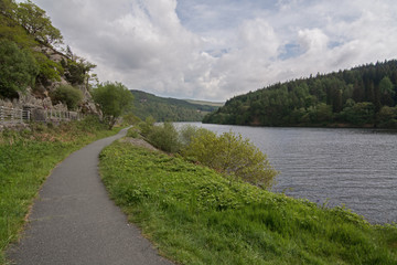 Footpath alongside a picturesque lake, with wooded hills
