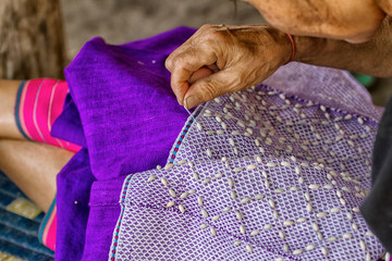 Woman hand stitching cloth to make ancient Thai pattern fabric