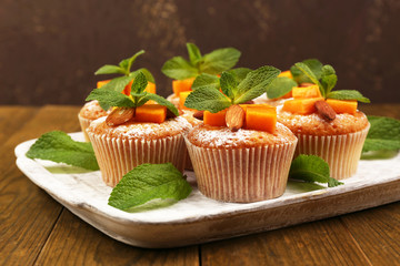 Tasty pumpkin muffins on wooden table