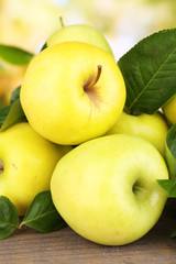 Ripe sweet apples with leaves on nature background