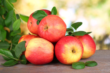 Ripe sweet apples with leaves on nature background