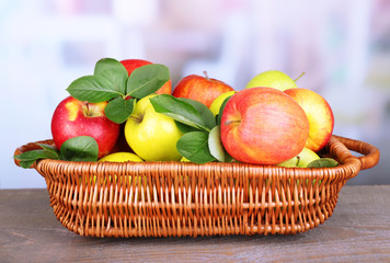 Ripe sweet apples with leaves in wicker basket