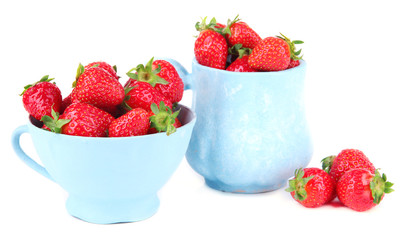 Ripe sweet strawberries in color mugs isolated on white