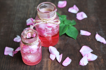 Rose oil in bottles on color wooden background