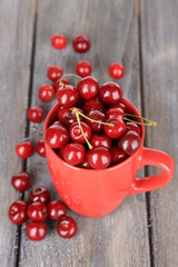 Sweet cherries in mug on wooden background