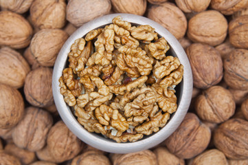 Walnuts in a wooden bowl on a walnuts pile