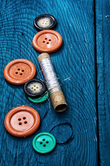 set of threads and buttons on the background of wood