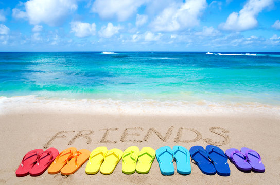 Sign "Friends" and color flip flops on sandy beach