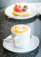 Cup of cappuccino coffee with sweet fruit tart cake on disc