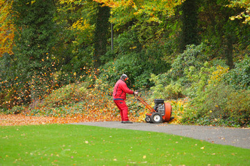 Angestellter entfernt Herbstlaub mit Laubgebläse im Park