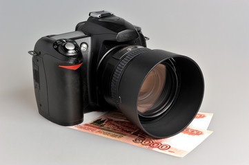 Photo camera with money on gray