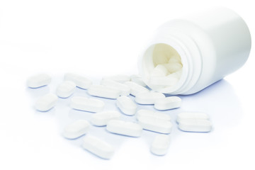 White pills spilling out of a medicine bottle