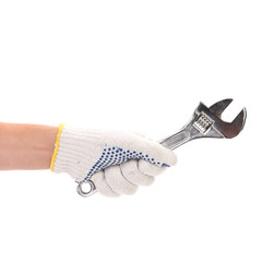 Hand in gloves holding adjustable wrench.