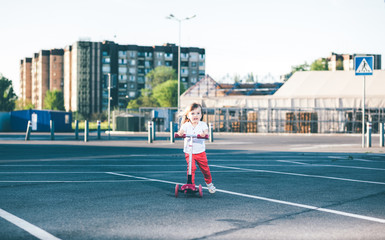 Fototapeta premium Little beautiful girl riding a scooter