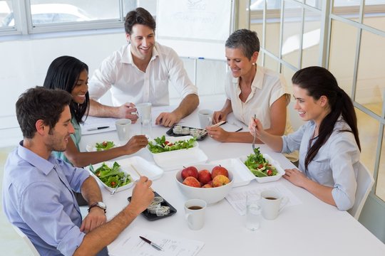 Workers eating fruit and salad together for lunch