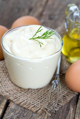 Mayonnaise in bowl with egg and olive oil on an old wooden table