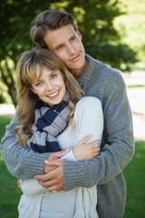 Naklejka premium Cute couple hugging with girl smiling at camera in the park