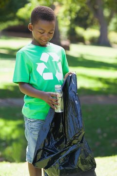 Young boy in recycling tshirt picking up trash