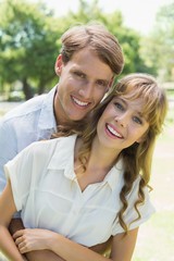 Attractive couple embracing and smiling at camera in park