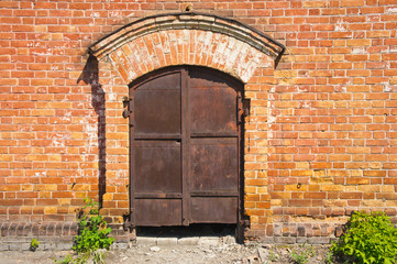 Fototapeta na wymiar old rusty iron gate in the brick wall