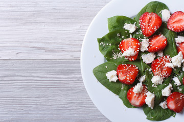 Salad of spinach, strawberries and cheese top view closeup