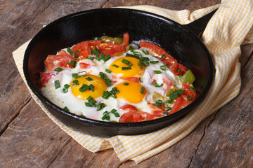 Fried eggs with tomatoes and onions in a pan
