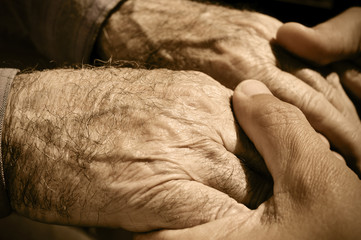 young man holding the hands of an old man