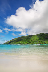 Sandy beach with green hill and blue sky background at Ephelia r