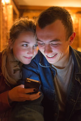 Fototapeta premium The young man and the girl look cellular telephon