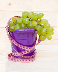 Ripe green grapes in pail on wooden table
