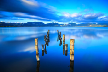 Obrazy na Szkle  Drewniane molo lub molo pozostaje na niebieskim jeziorze, zachód słońca i odbicie nieba