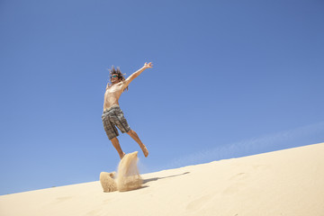 young man jumping happy in the desert