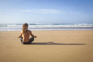 Fototapeta na wymiar young handsome man doing yoga meditation on the beach
