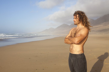 Fototapeta na wymiar young handome man looking at the ocean on a desert beach