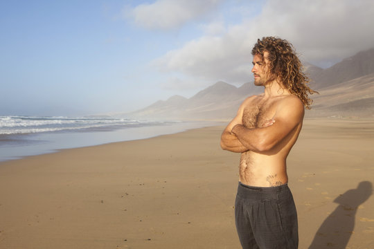 young handome man looking at the ocean on a desert beach