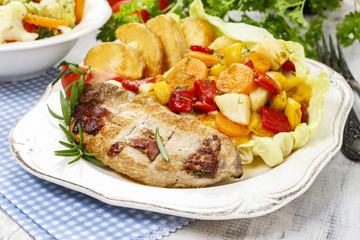 Joint of pork with baked potatoes and fresh vegetables