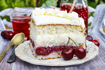 Cherry and coconut layer cake on wooden table in the garden