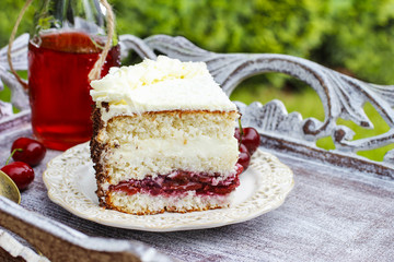 Cherry and coconut layer cake on wooden table in the garden