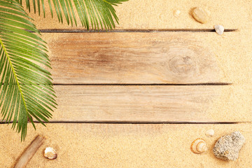 Palm tree leaves and sand on wood background