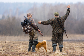zwei Jäger und Hund auf dem Feld